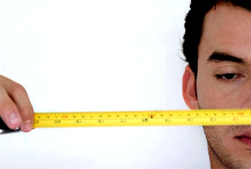 Mann mat Lineal moosst Penis virun der Erweiderung